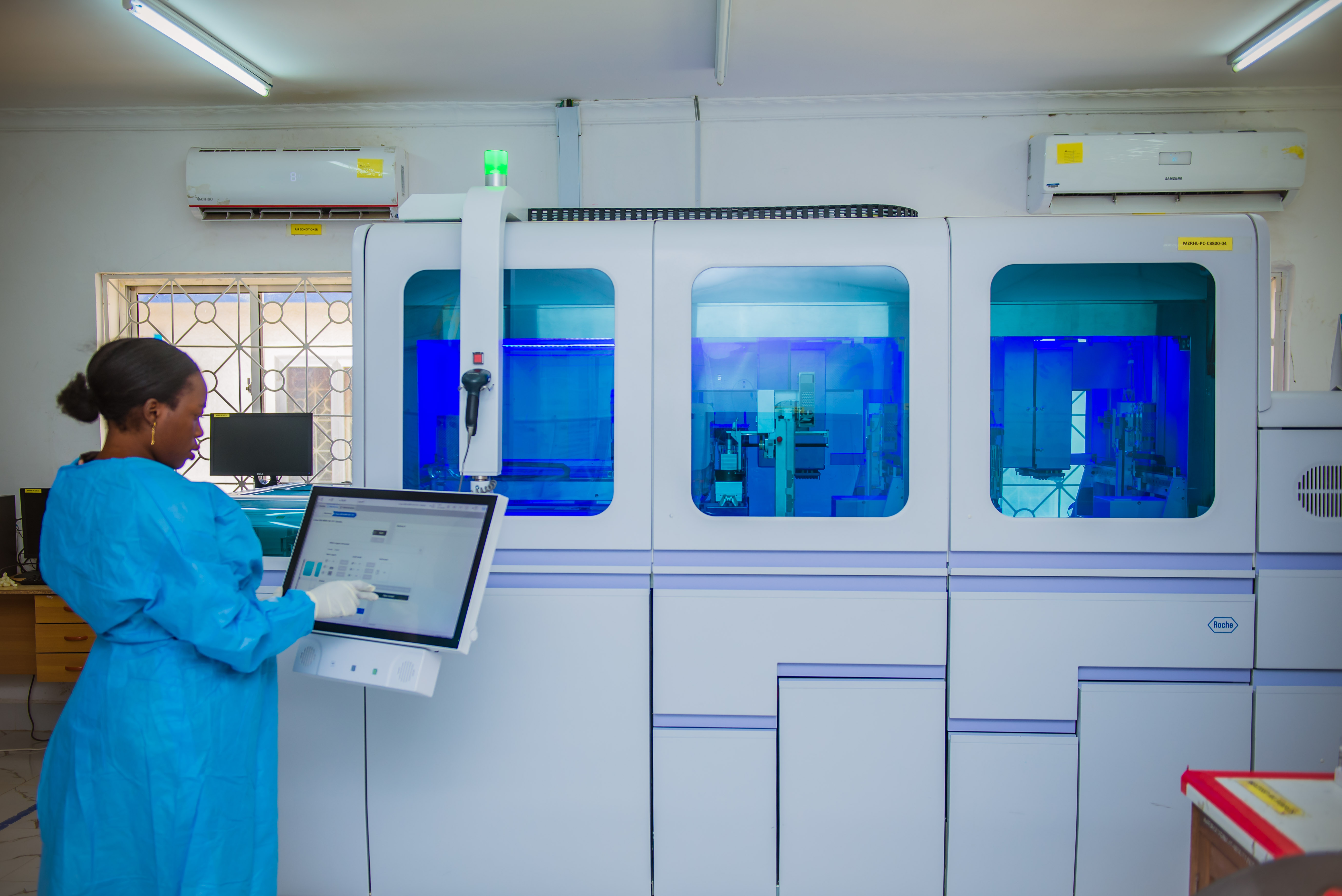 Woman stands at screen in front of lab equipment.