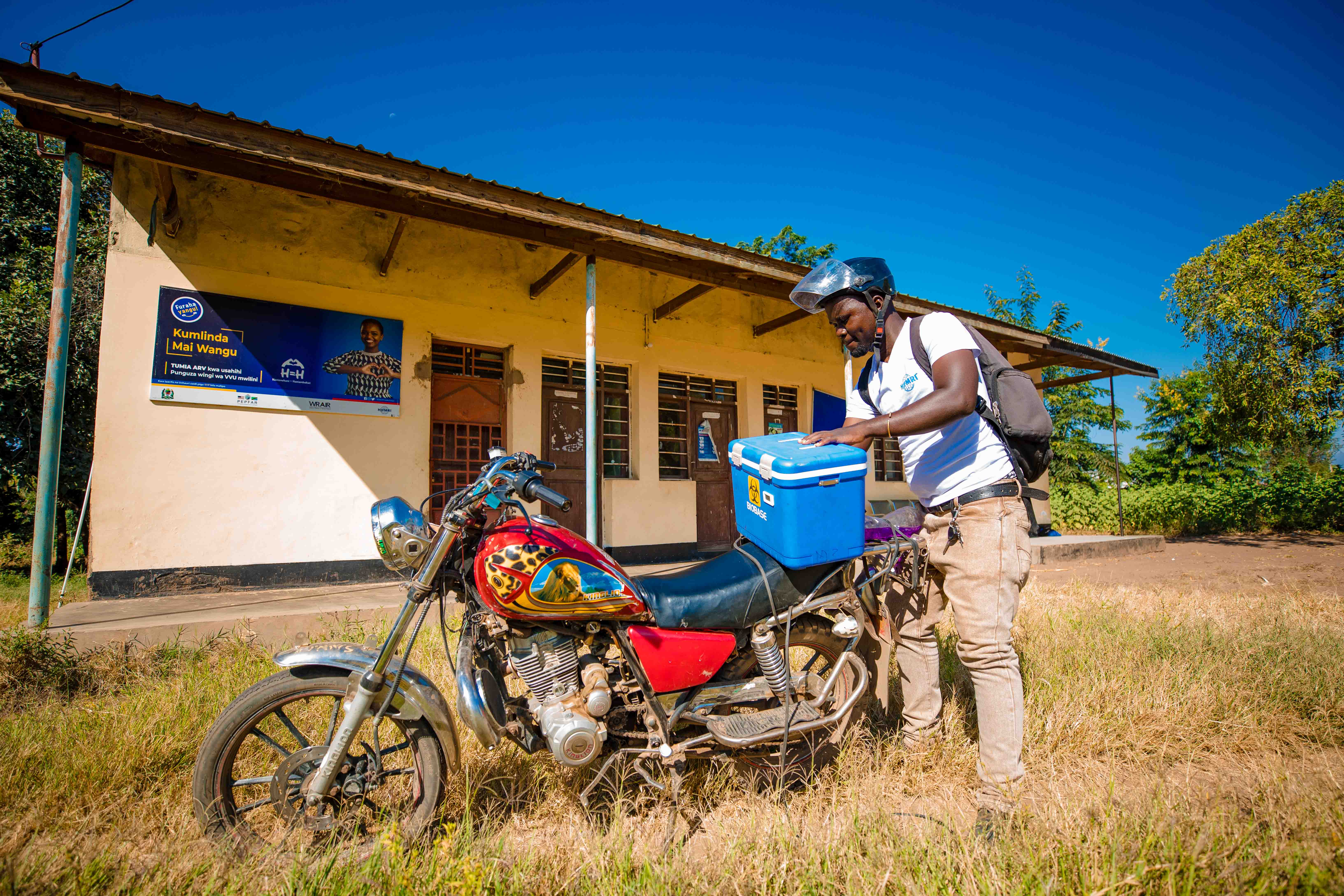 A man packs a sample cooler onto a motorcyle