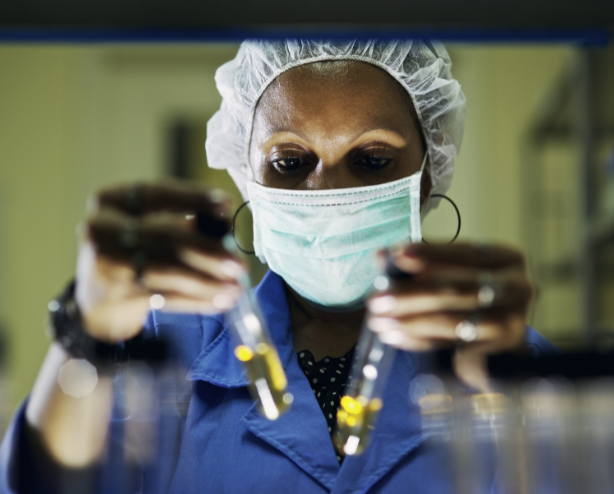 Black woman in mask holds up test tubes
