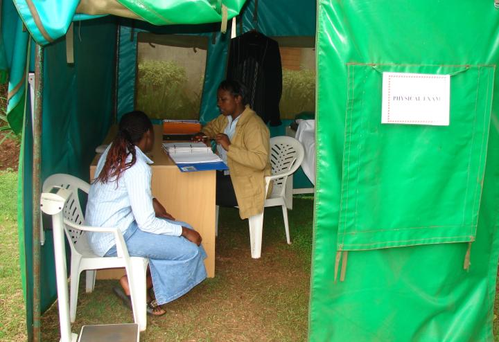 Clinicians talk in a green tent