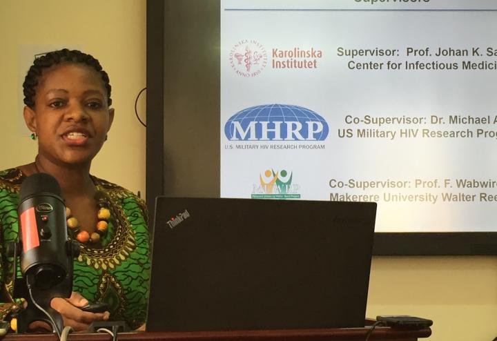 A woman standing at a podium in front of a PowerPoint presentation