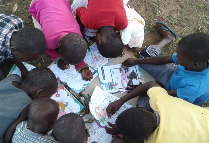 Children lie on the ground coloring pictures