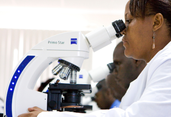 Kenyan woman studies a microscope next to several of her fellow students at the Kenyan Medical Research Institute