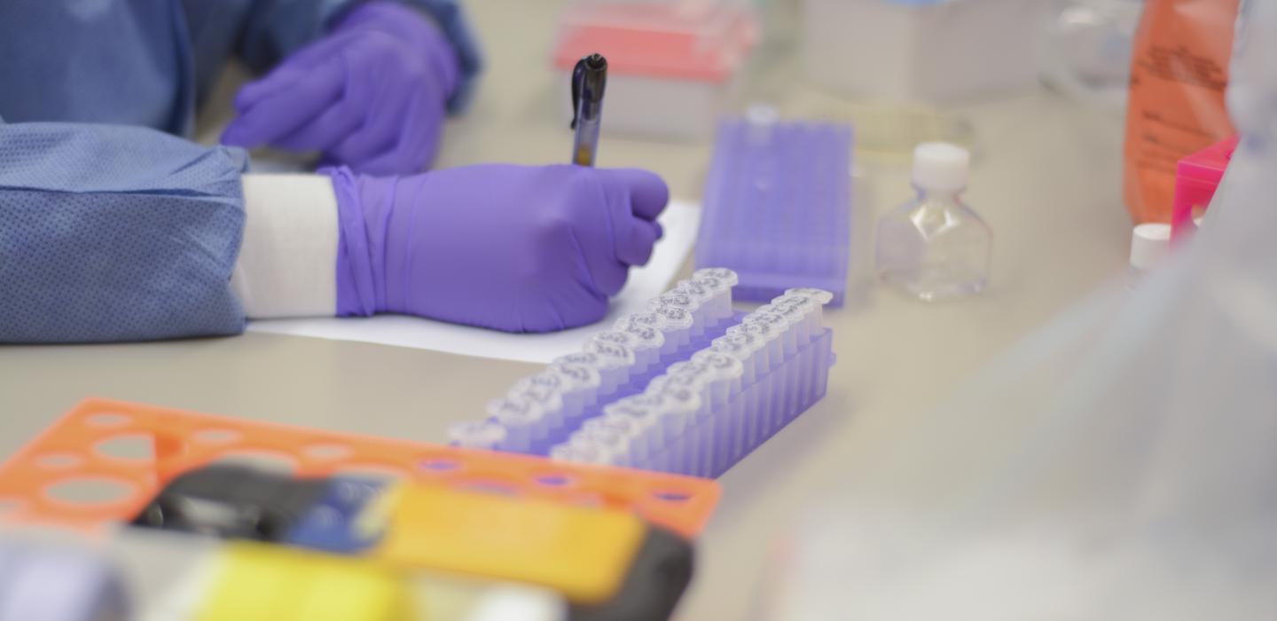 A scientist writes notes at a lab bench