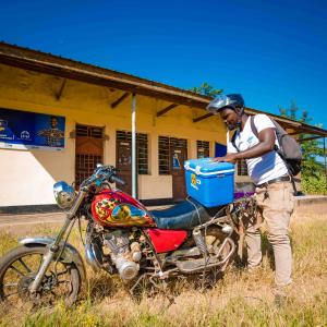 A man packs a sample cooler onto a motorcyle