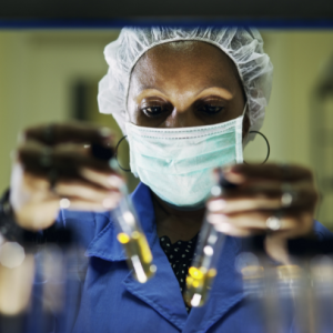 Black woman in mask holds up test tubes